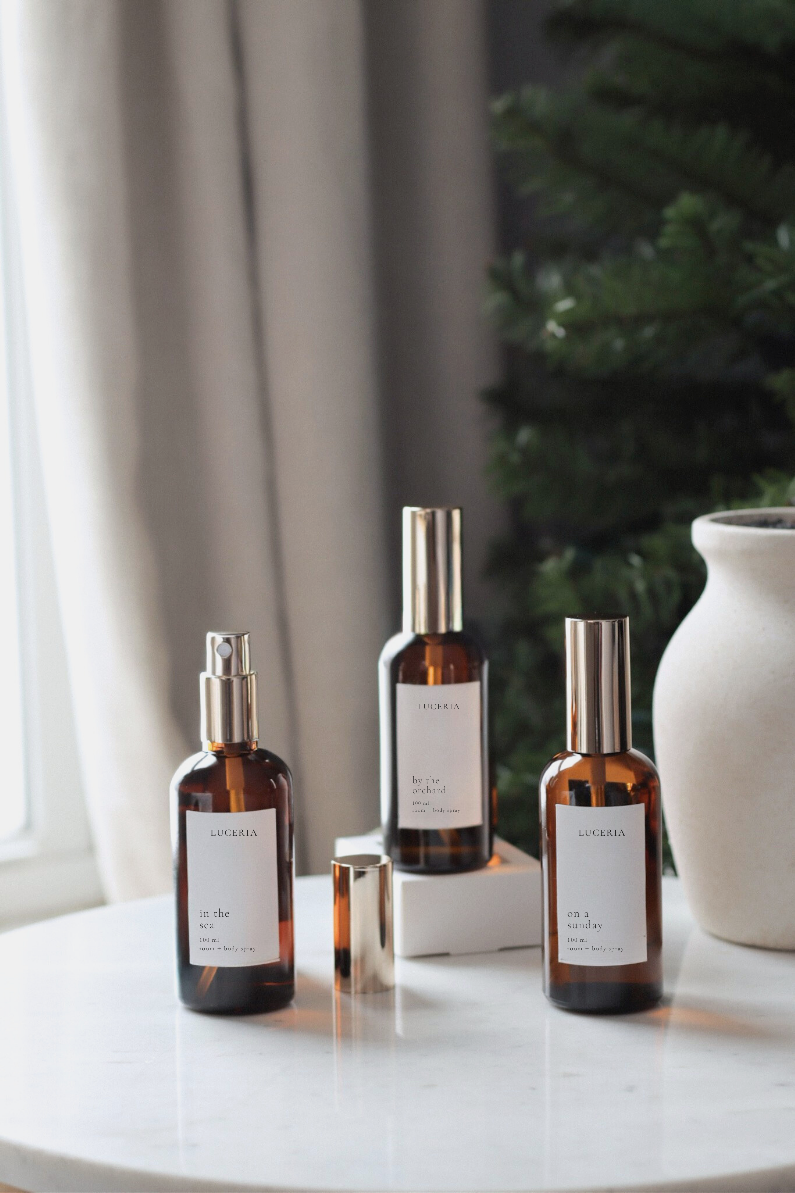 Luceria gentle room and body sprays in amber glass bottles with gold mist cap.