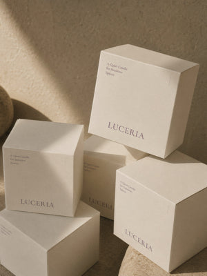 Luceria Candle Co.'s best selling candle product boxes stacked on top of each other on a natural surface stones and walls.