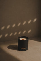 Ritual black matte soy candle with LUCERIA branding in neutral background