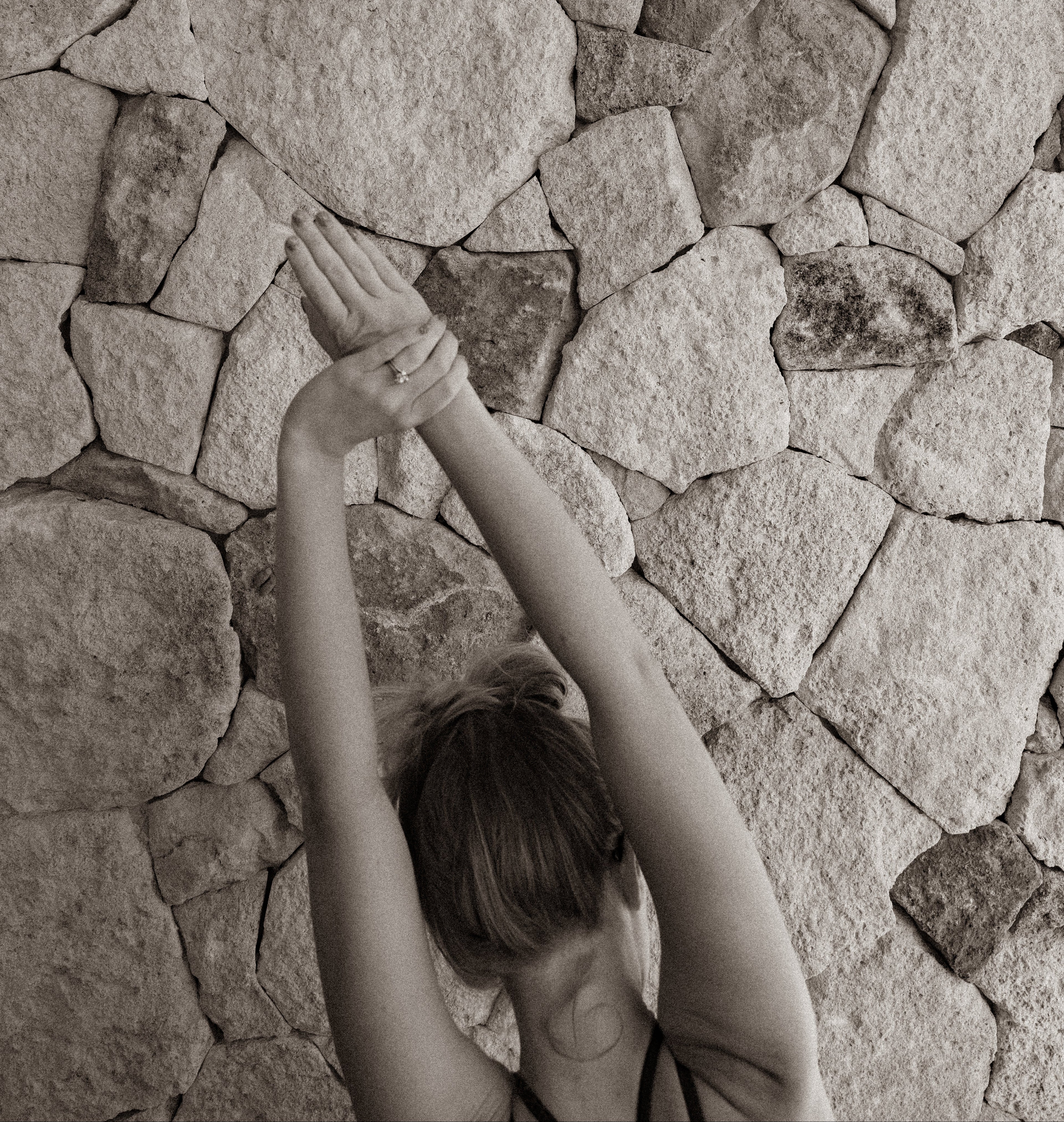 Person stretching with hands above head against a stone wall - Luceria Blog Post Page