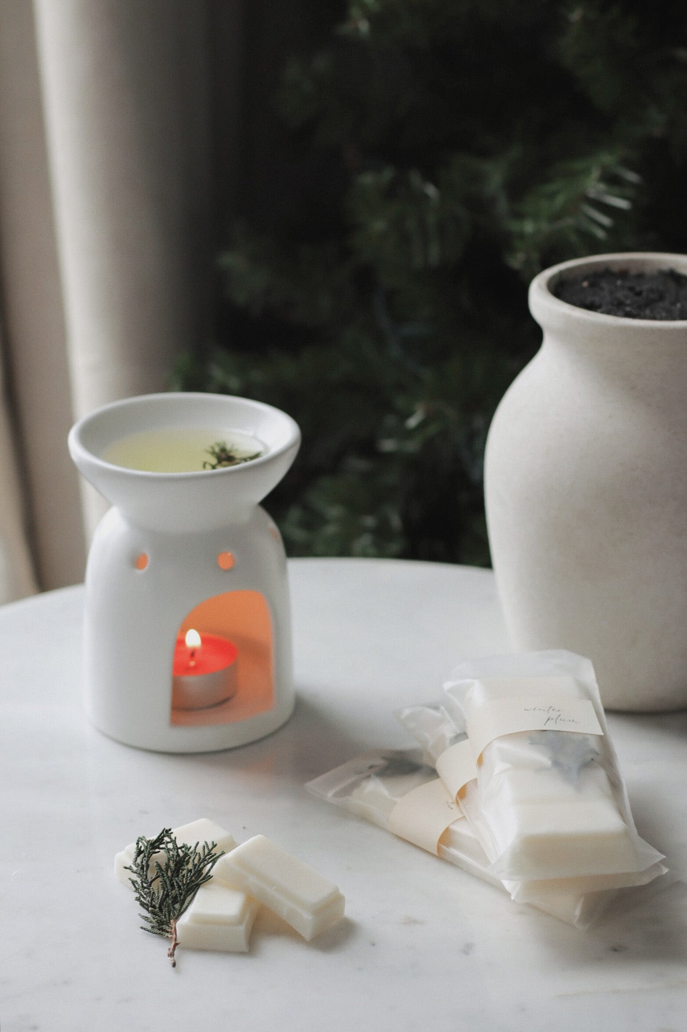 Aromatherapy diffuser with lit candle, tea bags, and a decorative plant on a table.