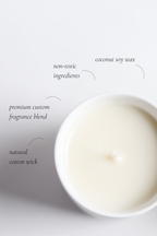 Cotton wick candle with text highlighting ingredients on a white background