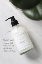 Hand soap bottle with label on a marble surface, featuring a plant in the background.
