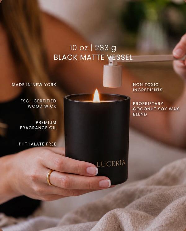 A black matte candle vessel labeled 'LUCERIA' with a lit flame is held by a person's hand, while another hand uses a wooden wick holder to add a wood wick. White text overlays highlight product features and ingredients.