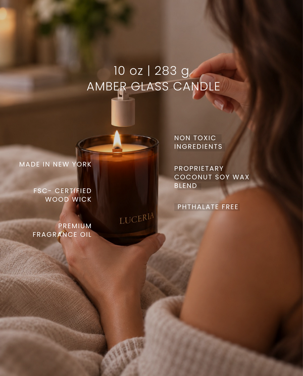 A person in a cozy bedroom setting holds an amber glass 'LUCERIA' candle with a lit wick and flame. White text overlays highlight product features such as '10 oz | 283 g AMBER GLASS CANDLE' and other scent and material claims.