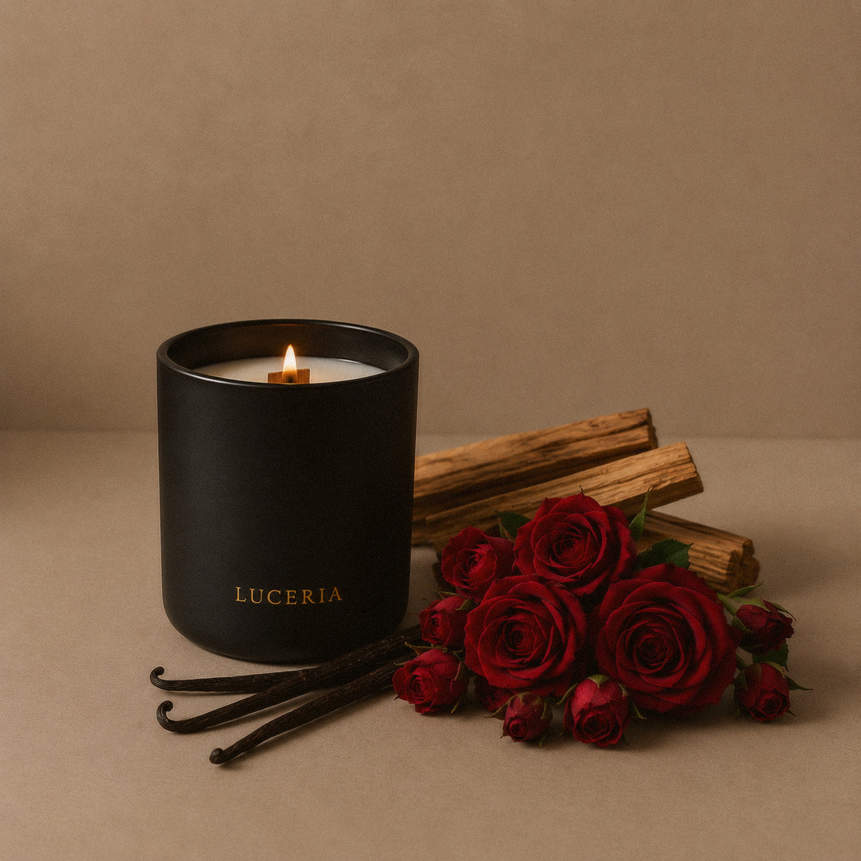 Luceria Veil Sandalwood + Rose candle in a matte black vessel styled with red roses, vanilla beans, and palo santo on a warm neutral linen backdrop.