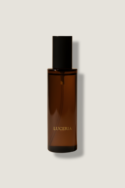 Brown spray bottle with black cap on a light gray background, featuring the brand 'LUCERIA'.