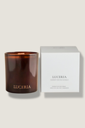 Brown candle with 'LUCERIA' branding next to its packaging on a light beige background