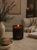 Luceria Lavender and Cedar candle in a amber glass vessel with a natural wood wick, styled in a calm neutral setting inspired by fresh linen and cedar.