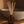 Amber glass reed diffuser bottle with natural wood reeds, labeled LUCERIA, placed on a wooden shelf in front of a speckled ceramic bowl.