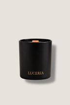 Black candle with 'LUCERIA' branding on a light beige background