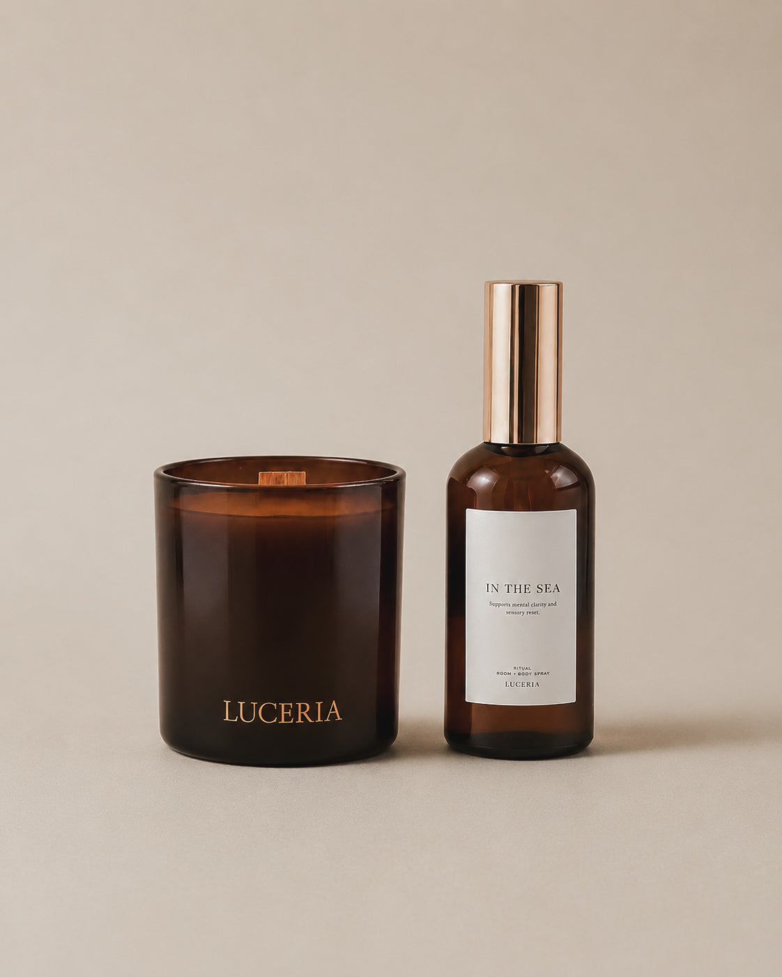 Luceria Candle Co coconut soy wax candle with wood wick and amber spray bottle set on a neutral backdrop with soft diffused lighting. 