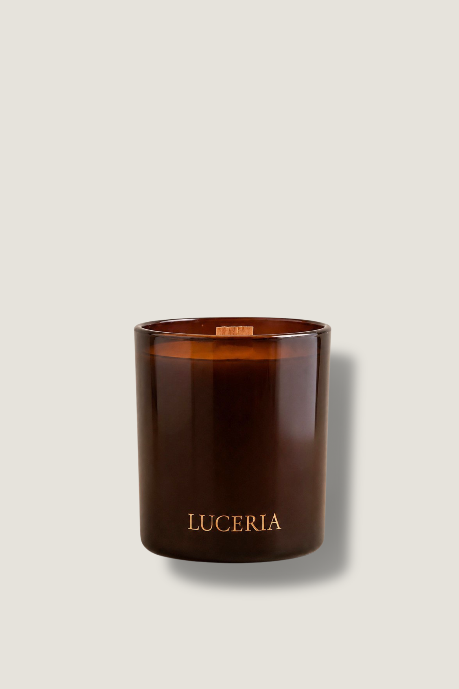 Brown candle with 'LUCERIA' branding on a beige background