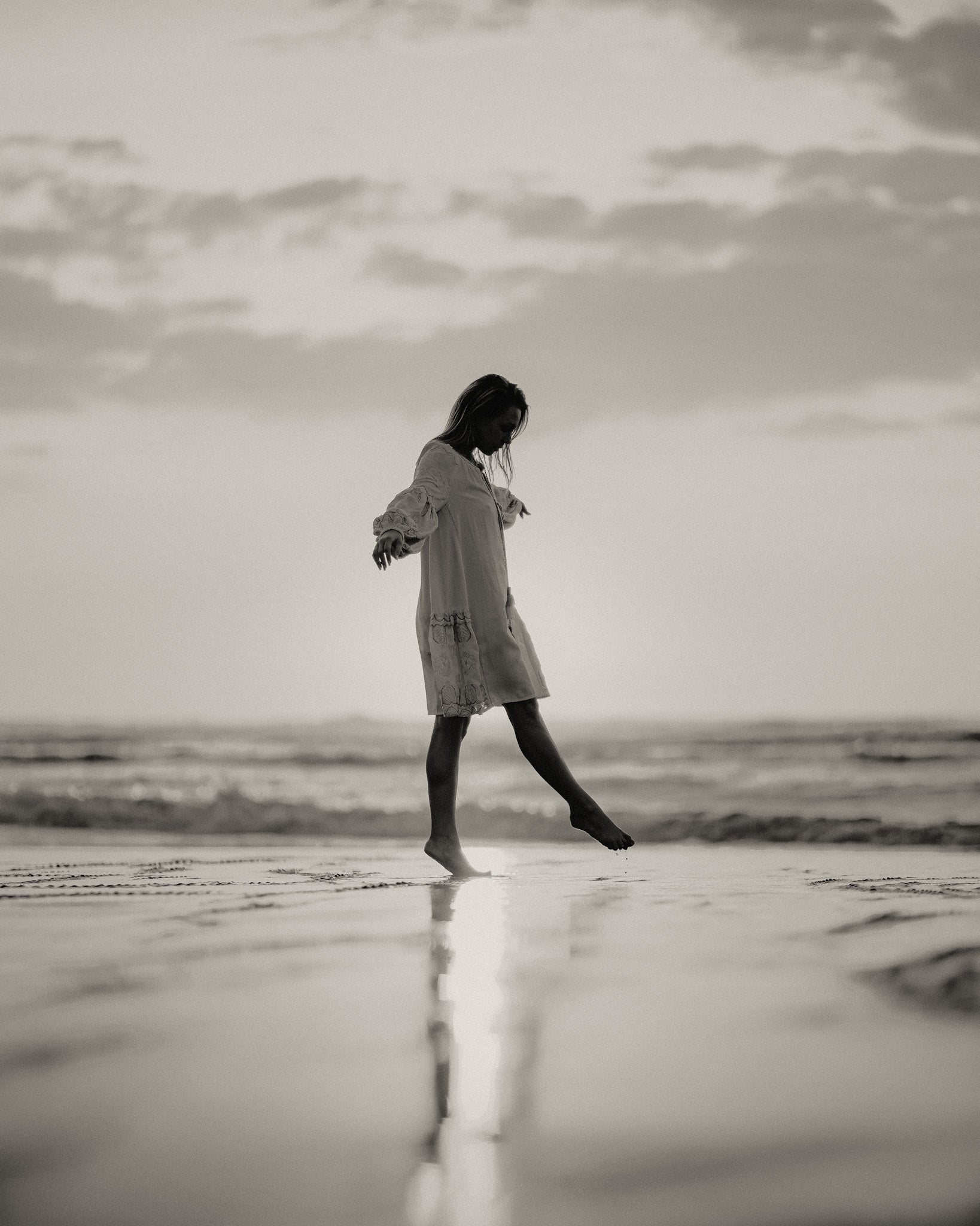 Person walking on a beach with a cloudy sky