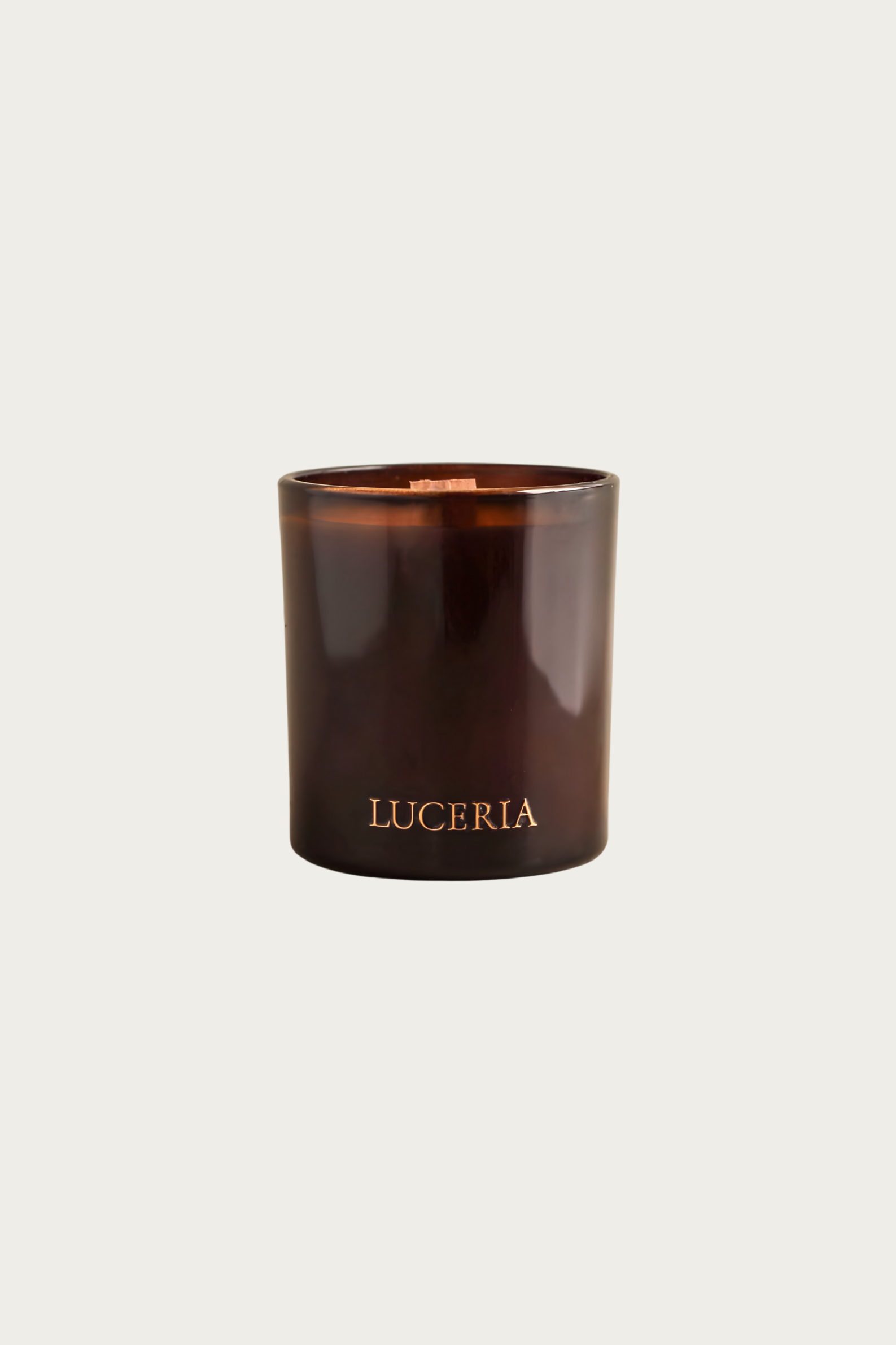 Brown candle with 'LUCERIA' branding on a light beige background