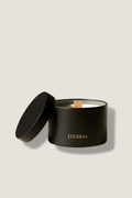 Black candle in a container with 'LUCERIA' branding on a beige background