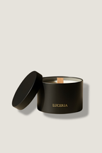 Black candle in a container with 'LUCERIA' branding on a beige background