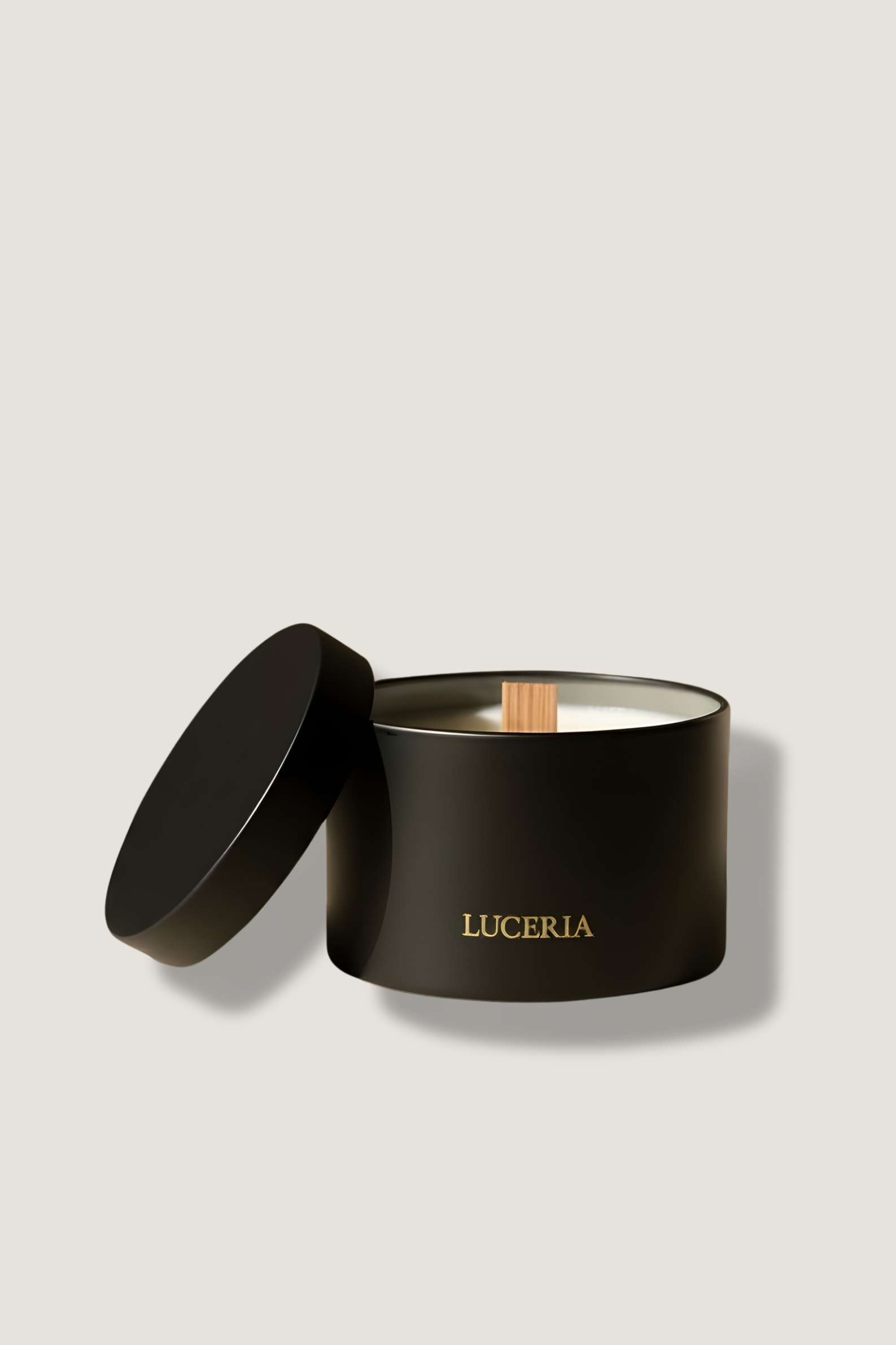 Black candle in a container with 'LUCERIA' branding on a beige background