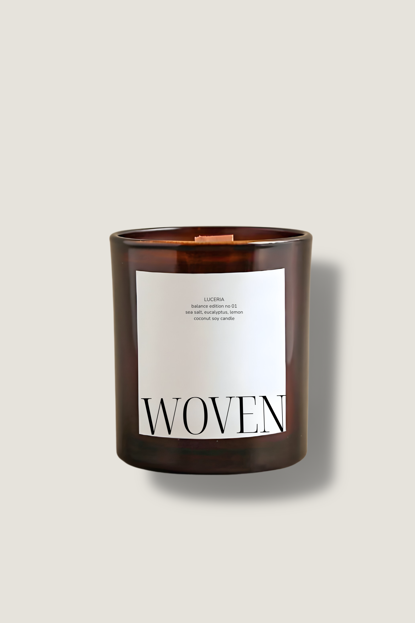 Candle with a wooden lid and 'Woven' label on a beige background