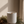 White ceramic Luceria candle scented with oakmoss and white cedar, featuring a natural wood wick on a stone surface with moss and driftwood.