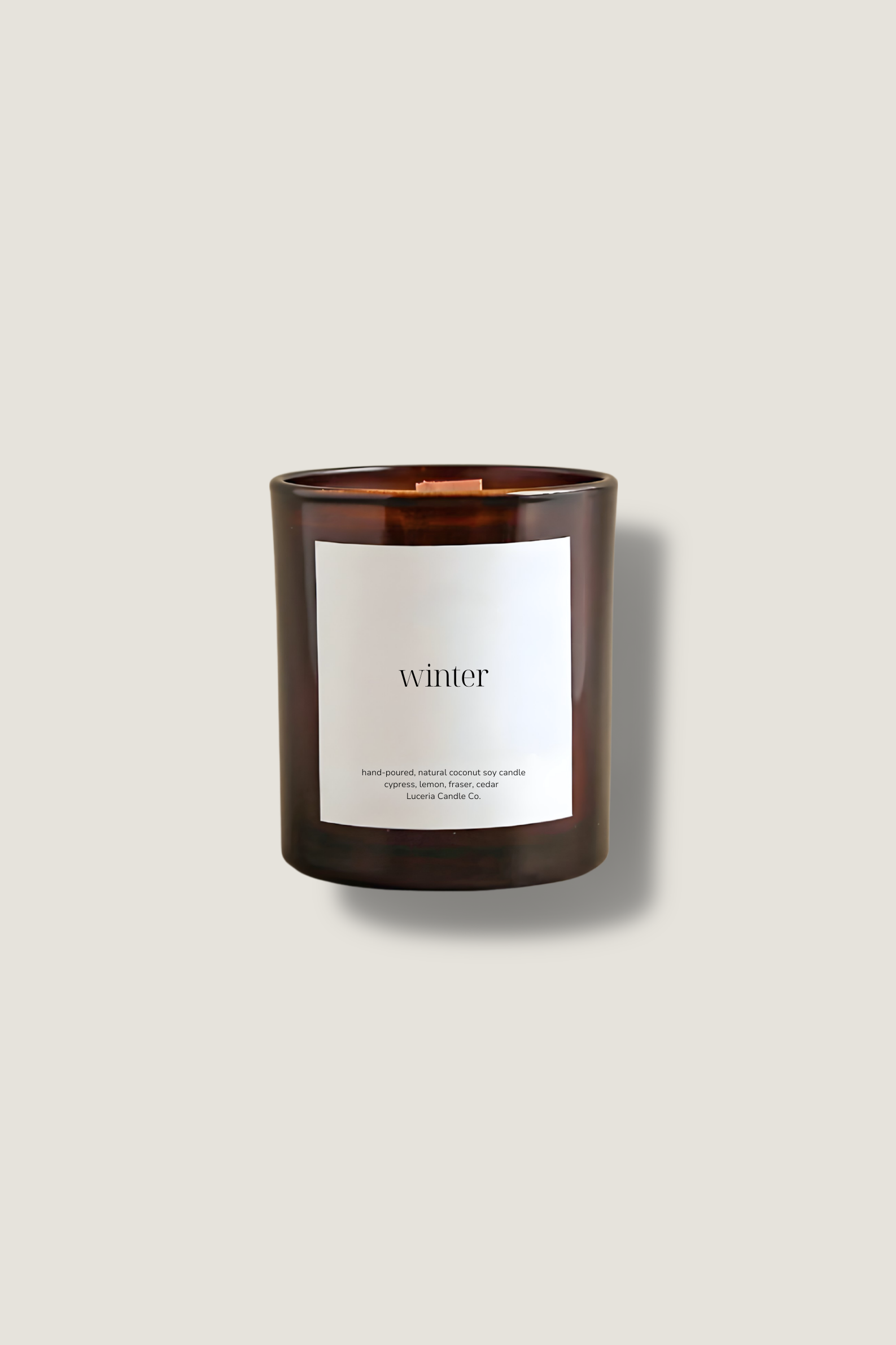 Winter candle in a brown jar with a white label on a beige background