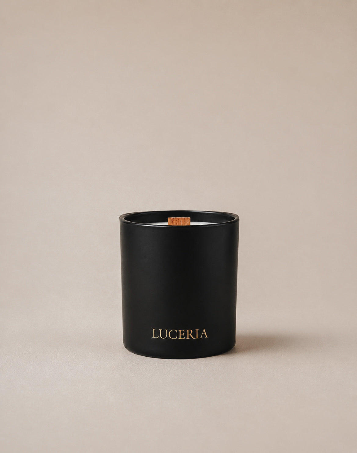 A Luceria black matte coconut soy wax candle with wood wick labeled ‘LUCERIA’ in gold lettering on a neutral beige backdrop with soft diffused lighting.