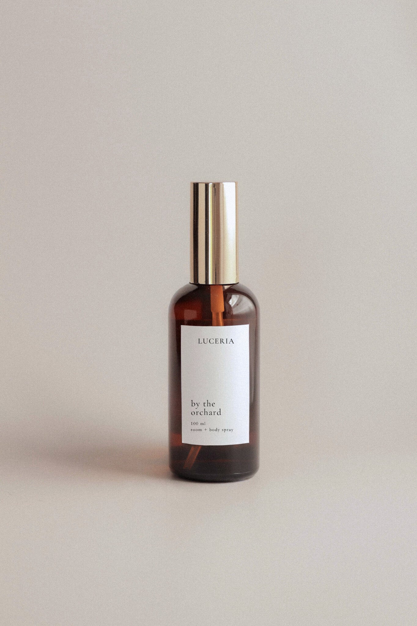 Persimmon Citron scented amber glass bottle with gold cap and white label on a light gray background