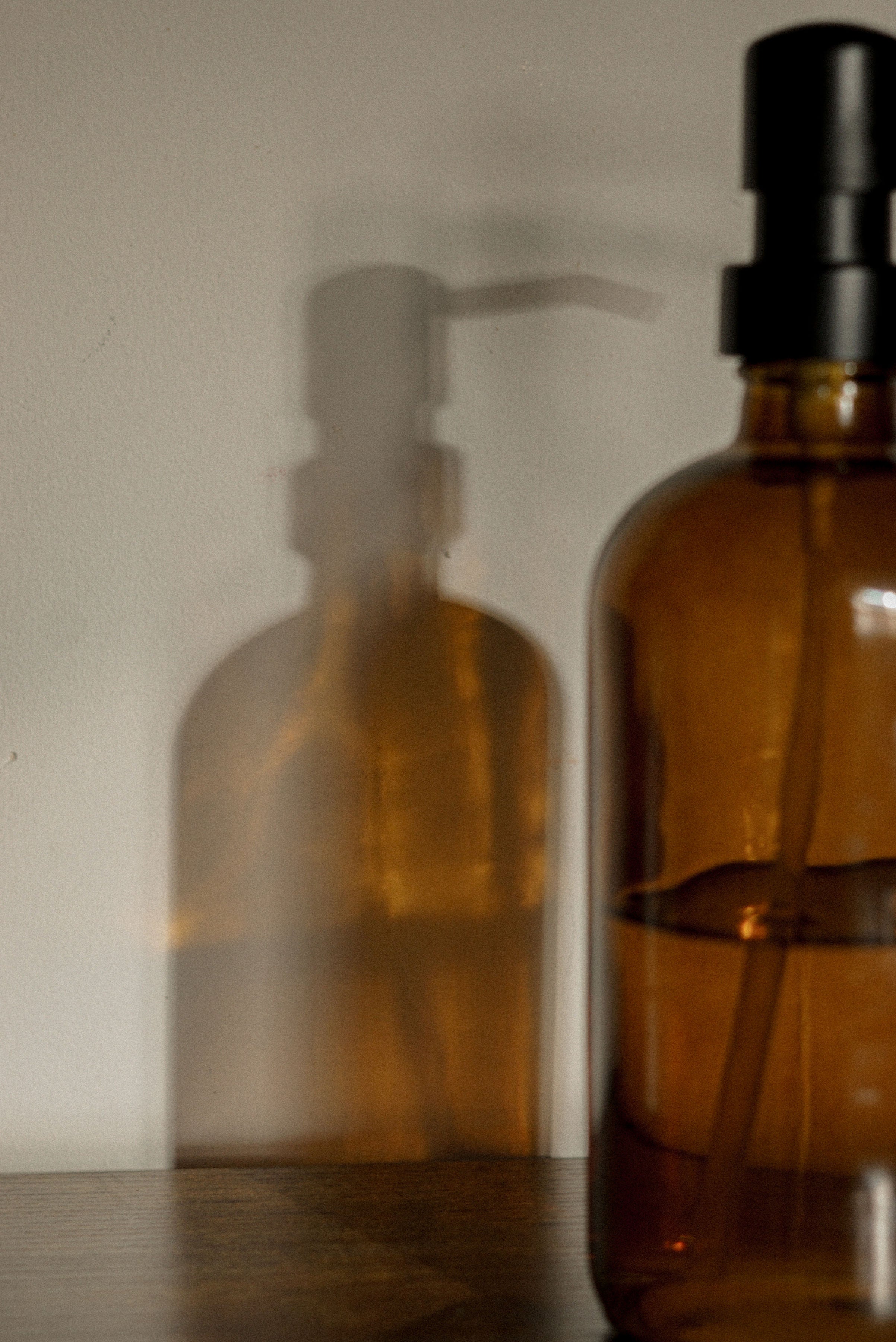 Two brown glass bottles with black caps on a reflective surface.