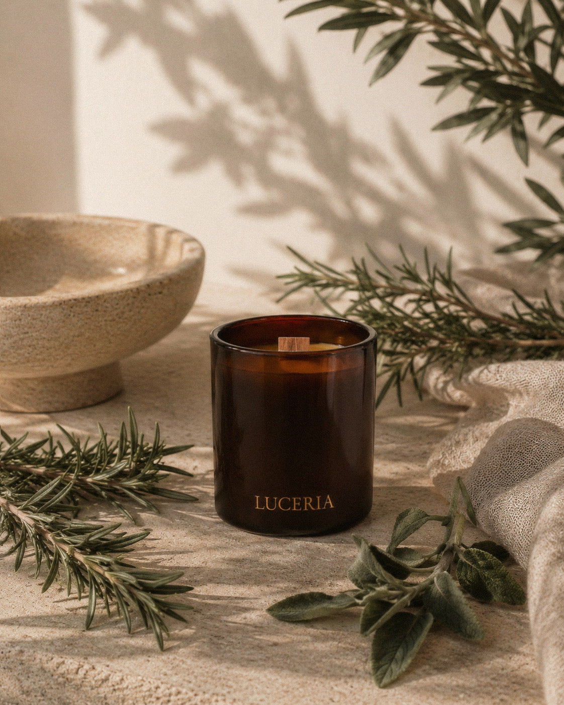 Luceria Candle Co.’s Rosemary and Sage Candle on a neutral background with rosemary sprigs and sage leaves