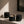 Three matte black LUCERIA candles in rounded glass jars, with the center candle lit and casting a warm glow, arranged on a beige stone ledge in soft sunlight. The Ritual Collection by Luceria Candle Co.