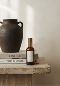 Brown bottle with a label on top of books next to a dark brown vase on a stone surface.