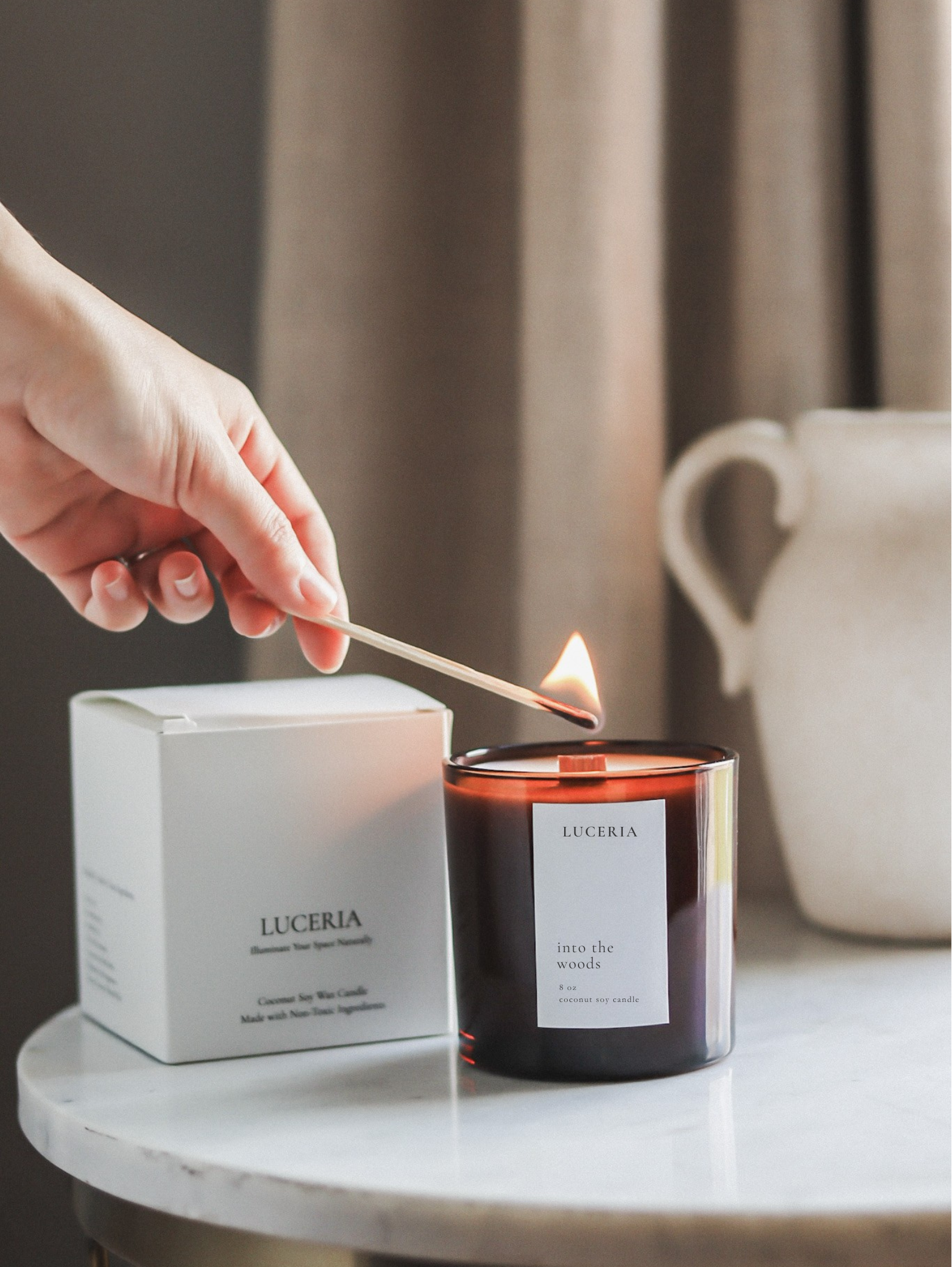 Person lighting a Luceria candle with a match on a marble surface.