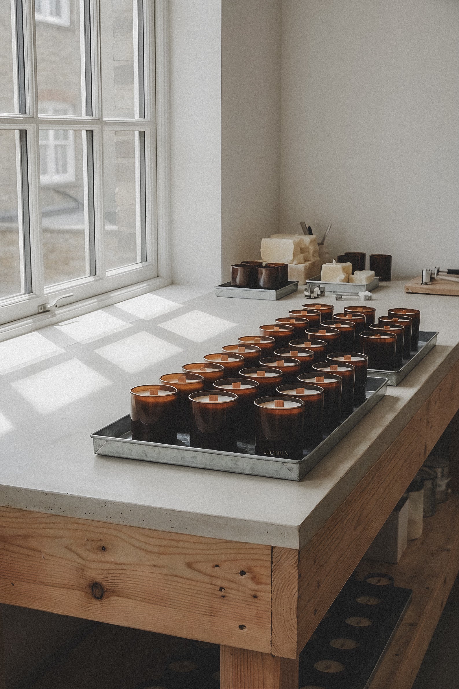 Tray of small round LUCERIA containers on a wooden table with a window in the background