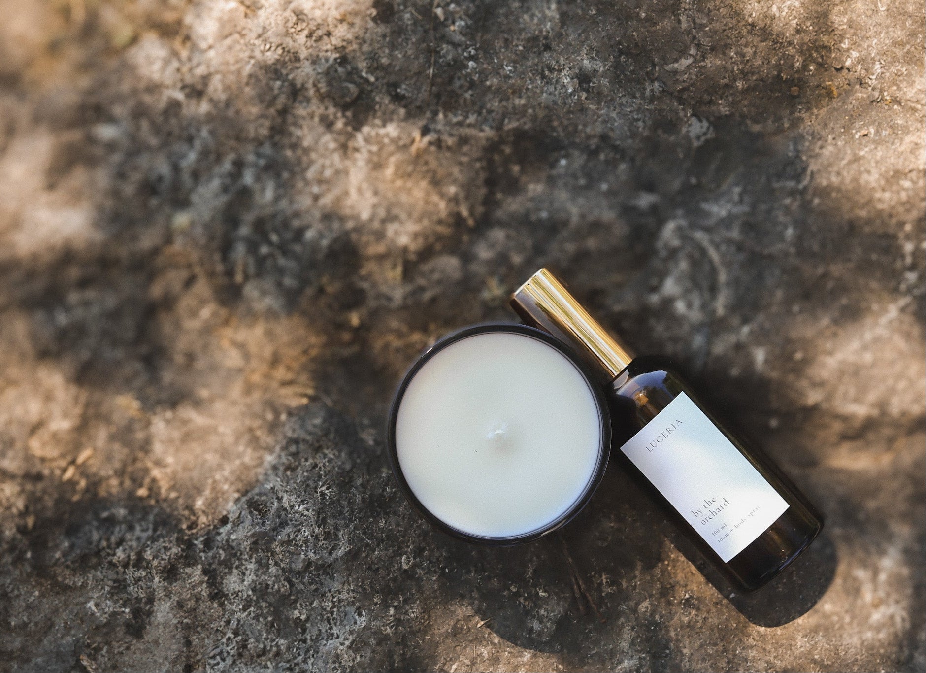 Luceria candle and room spray bottle on a natural textured stone surface
