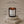 A lit Luceria amber glass candle with a white label reading 'REPOSE', displayed on stacked stone blocks against a warm beige background. Text around the candle highlights product claims such as 10 oz size, made in New York, natural wood wick, phthalate free, non toxic ingredients, and premium fragrance oil.