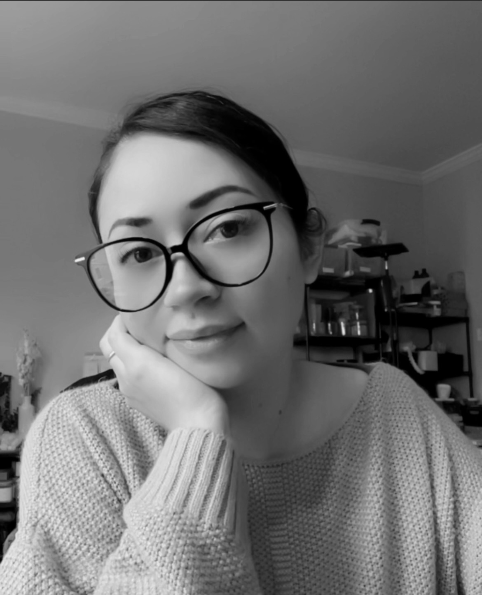 Black and white photo of Luceria Candle Co owner, Angel, wearing glasses with a blurred background