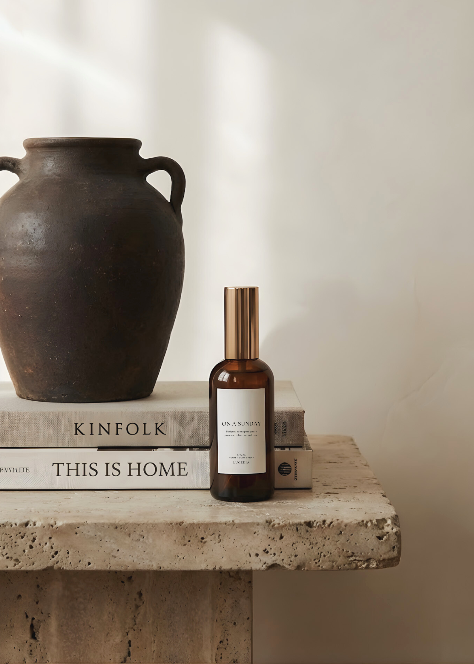 Brown bottle with a label on top of books next to a dark brown vase on a stone surface.
