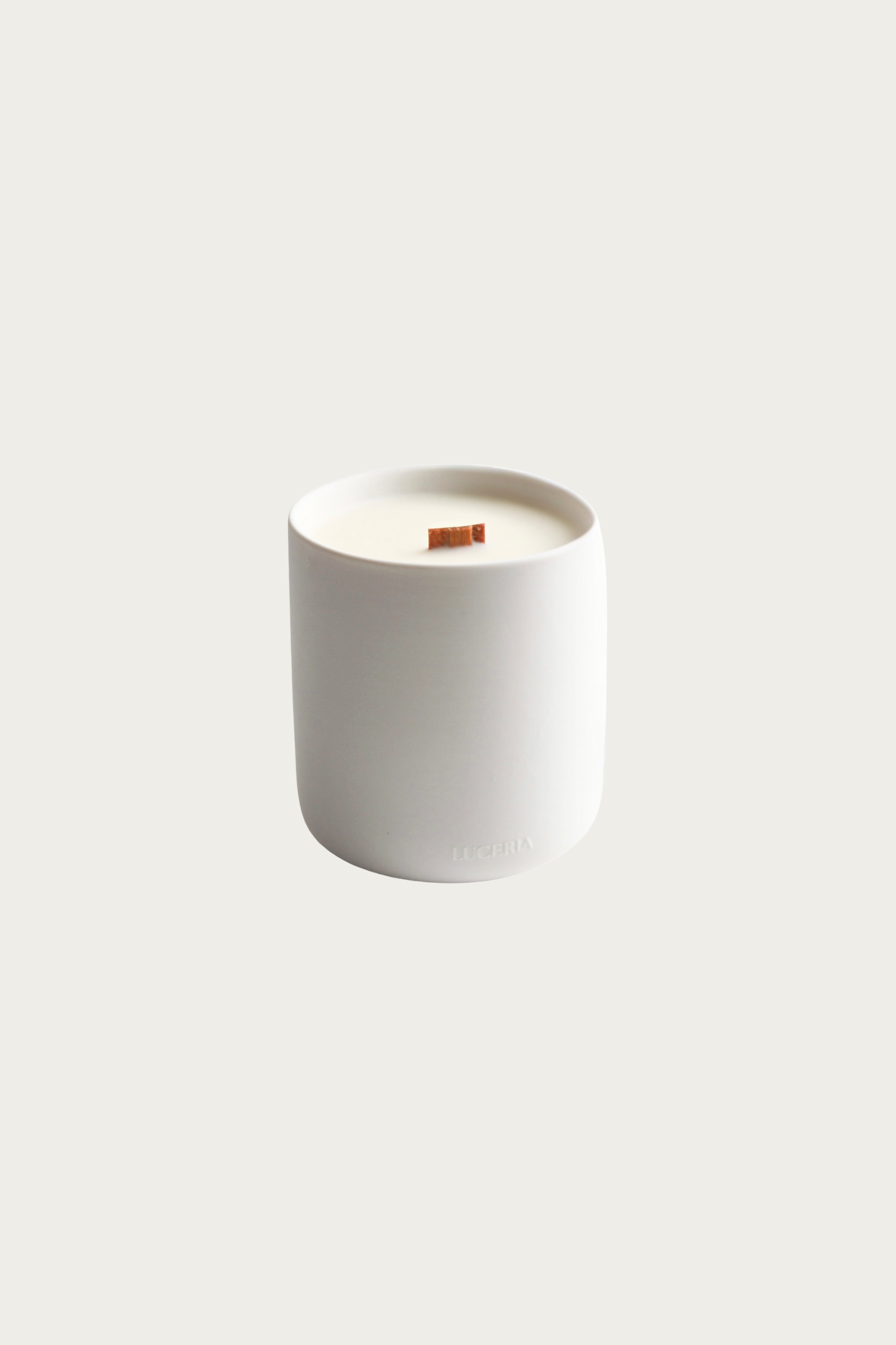 White candle in a cylindrical container on a white background