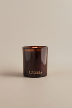 Brown candle with 'LUCERIA' branding on a beige background
