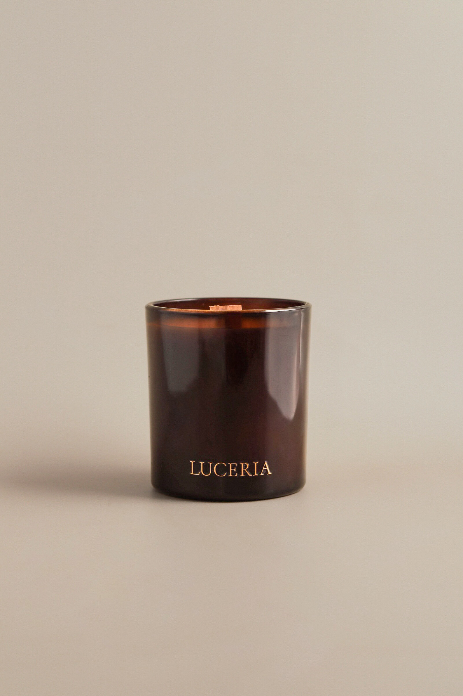 Brown candle with 'LUCERIA' branding on a beige background