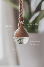 Wooden hanging diffuser with clear liquid, natural wooden cap, and text describing features.