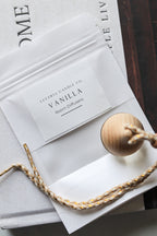 Scented car freshener with wooden diffuser on a textured surface.