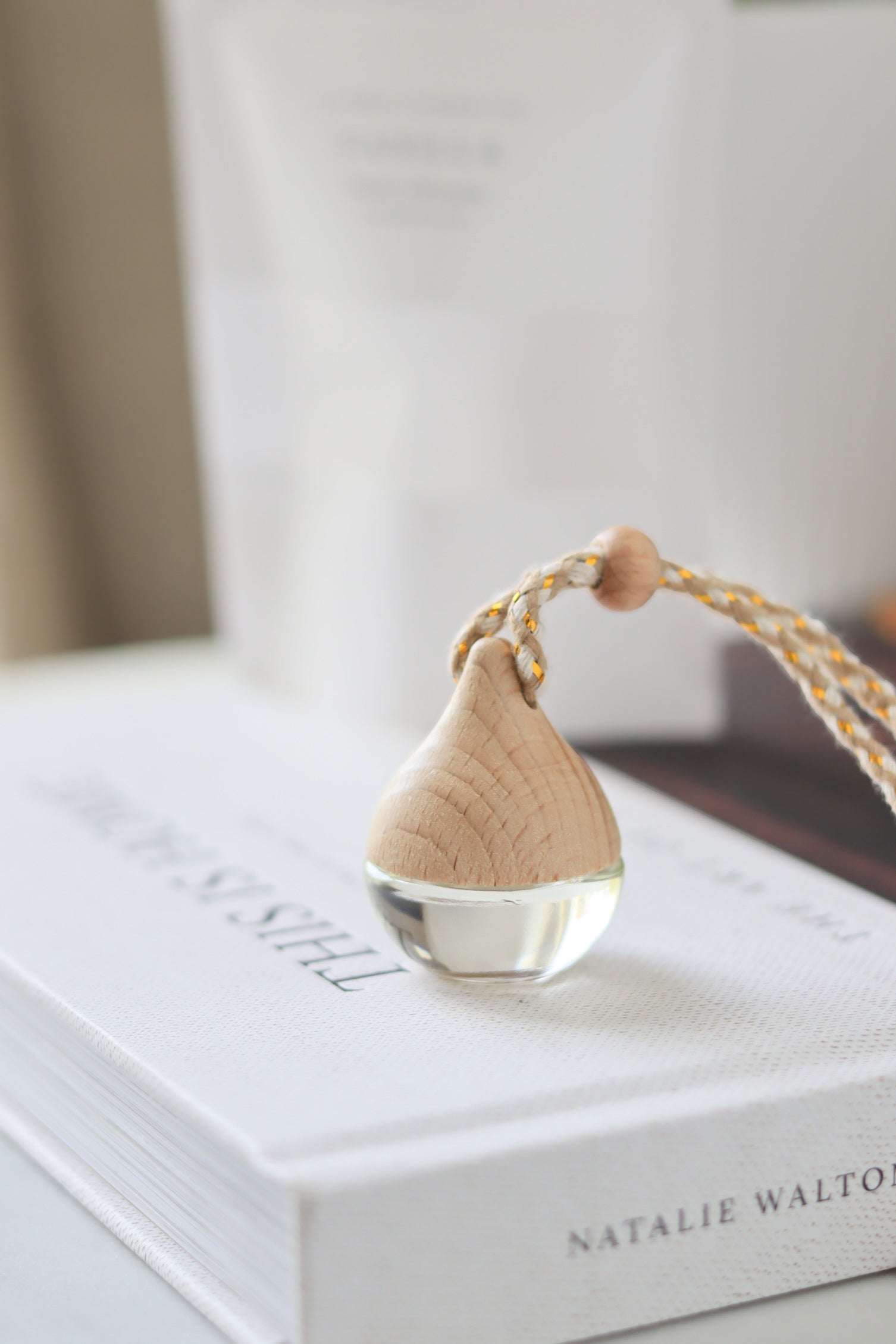 Wooden car diffuser with clear droplet on a book.
