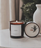 Candle with a label and decorative element on a surface with a blurred background