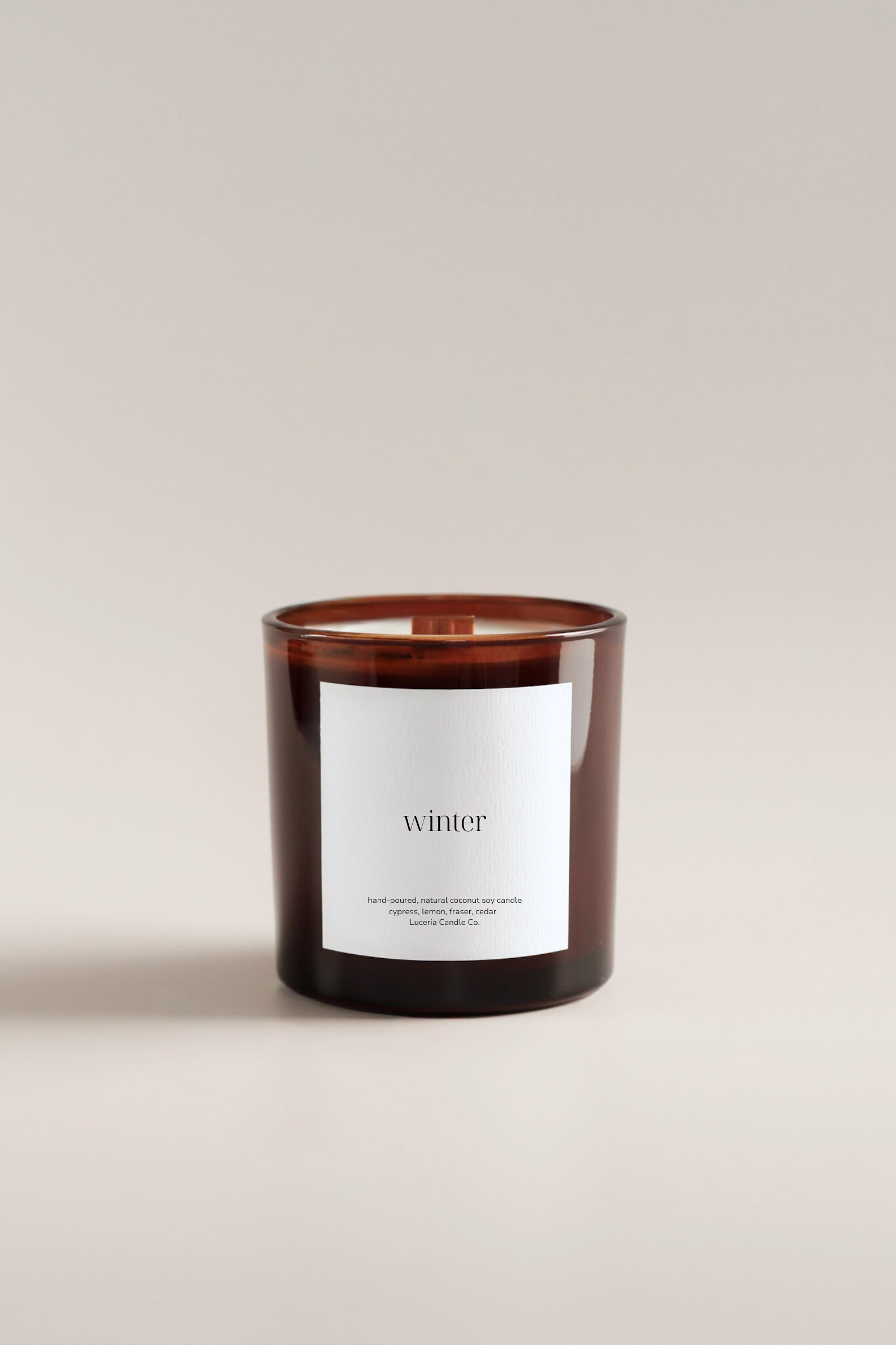 Holiday scented candle with a label reading 'winter' on a beige background