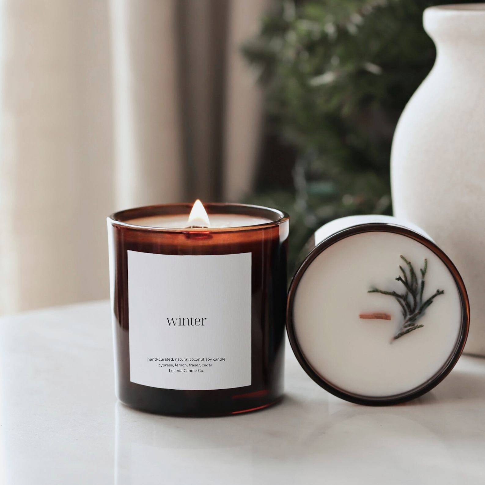 Fraser fir scented candle with a label and decorative item on a surface with a blurred background