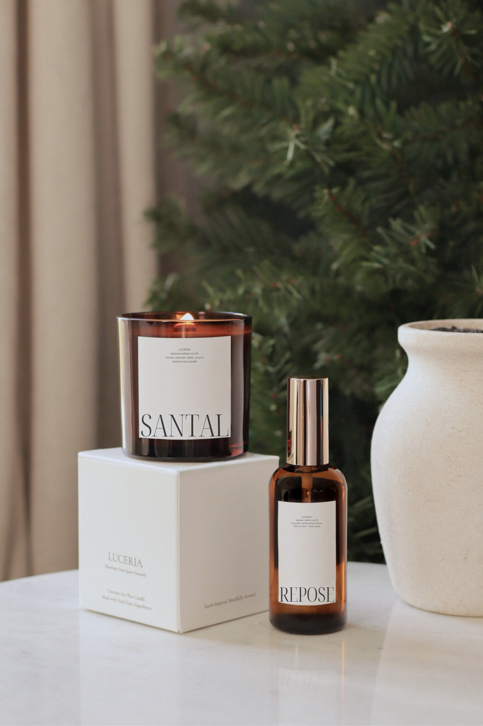 Candle and bottle labeled 'Santal' and 'Repost' on a surface with a Christmas tree in the background.