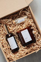 Amber glass candle and spray bottle with matches in brown Kraft box ready for gifting.