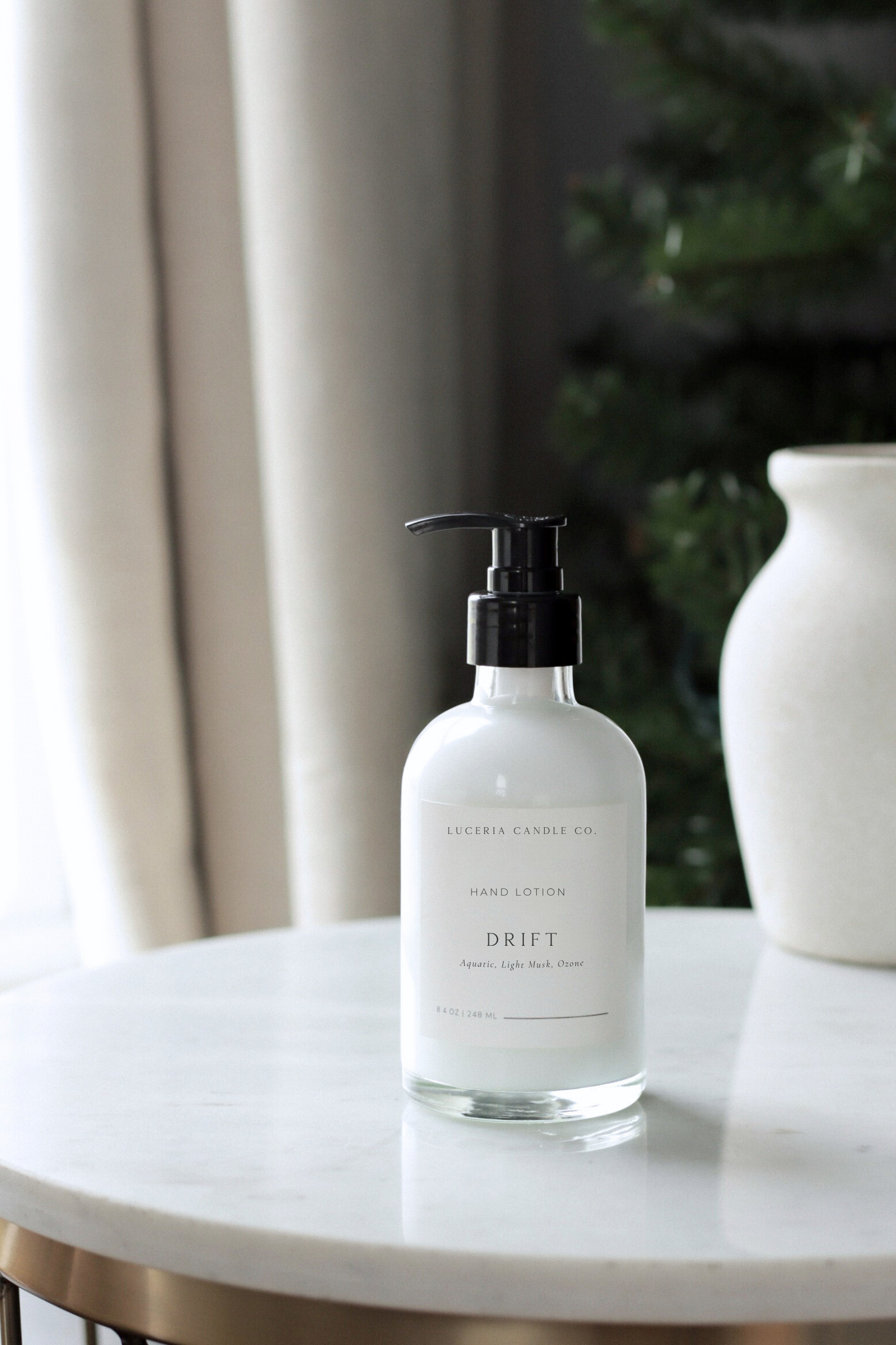 Hand lotion bottle labeled 'DRIFT' on a marble surface with a neutral background