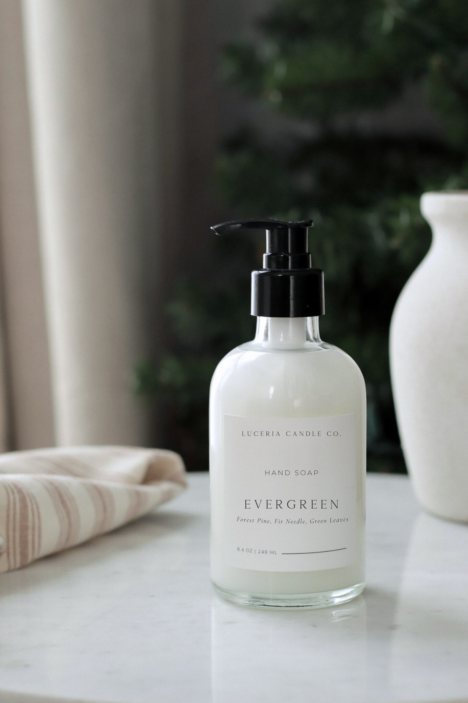 Hand soap bottle labeled 'Evergreen' on a surface with a blurred background